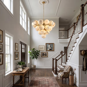 Large Lune chandelier illuminated in a tall entryway beside stairs