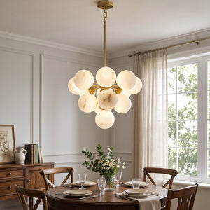 Illuminated Lune chandelier above a round dining table beside a window
