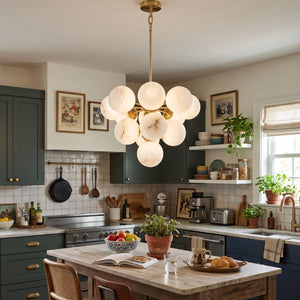 Illuminated Lune chandelier above a kitchen island with wooden stools