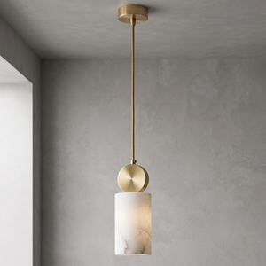 Cylinder alabaster shade glowing warm against a grey wall corner