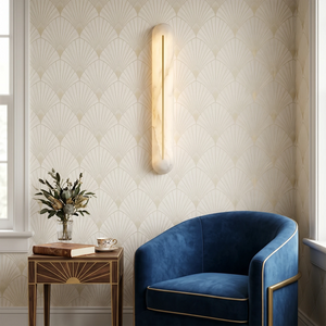 Hoailamp alabaster linear wall sconce on patterned wallpaper beside a blue accent armchair