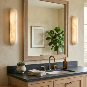 Pair of Hoailamp alabaster linear sconces flanking a bathroom vanity mirror above wooden cabinets