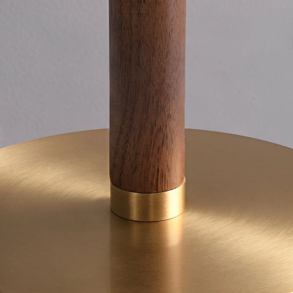 The walnut wood section of the stem above the brushed brass base.