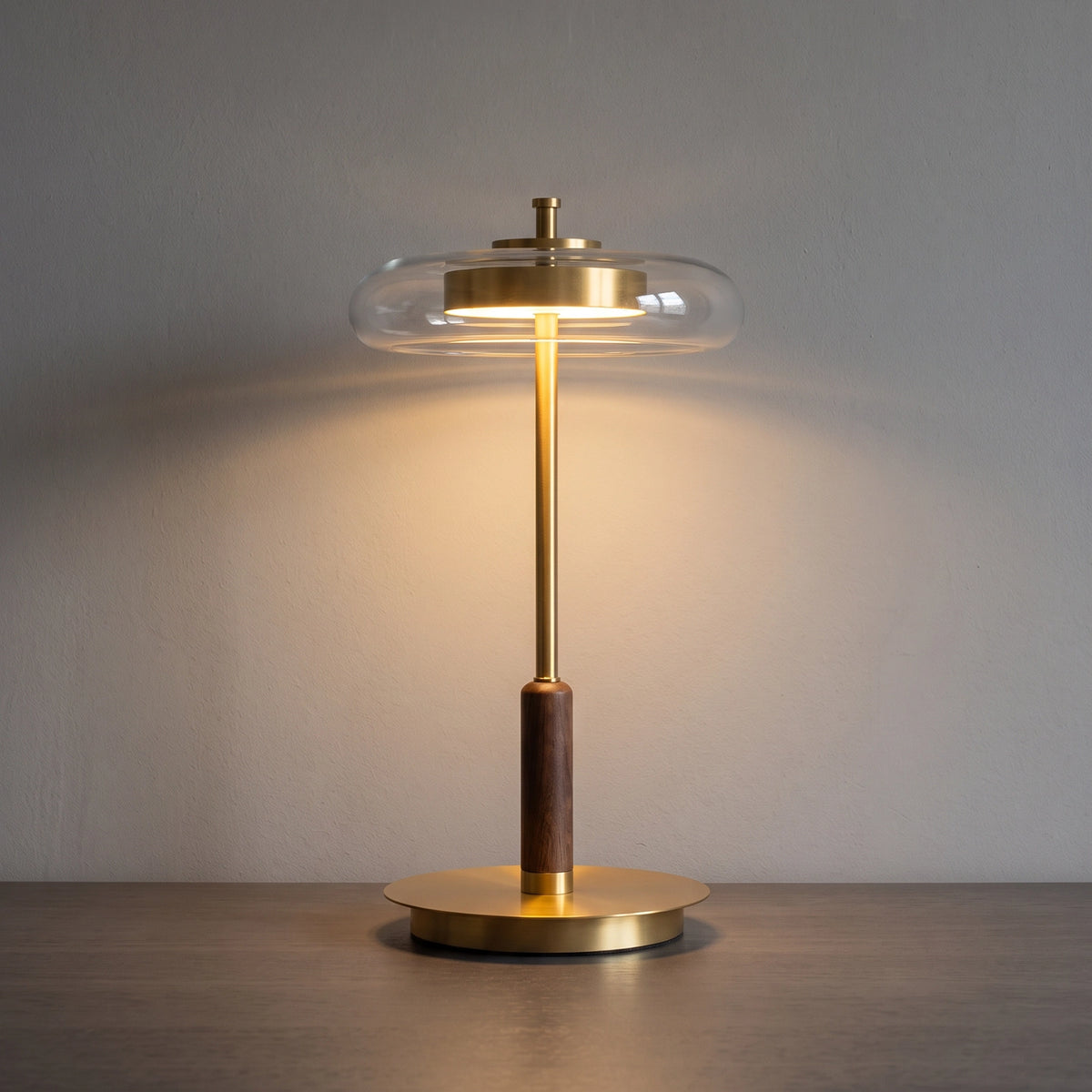The Loria lamp lit against a concrete wall, light falling from beneath its glass halo.