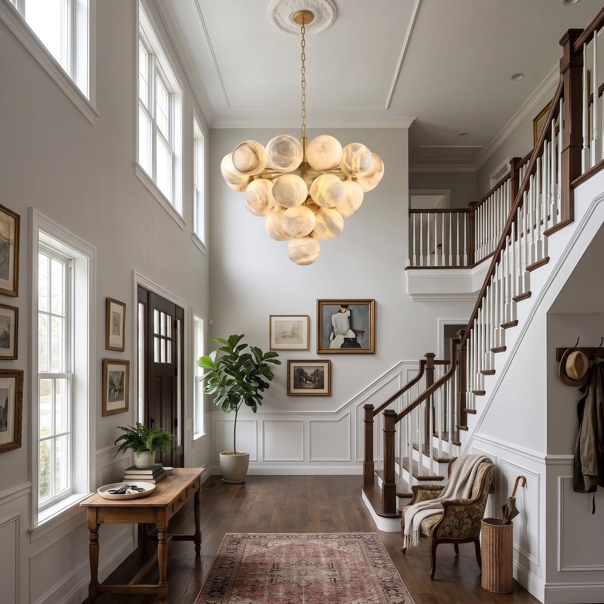 Large Lune chandelier illuminated in a tall entryway beside stairs