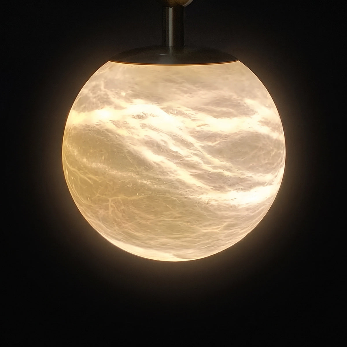 Illuminated alabaster globe showing cloudy veining against a dark background