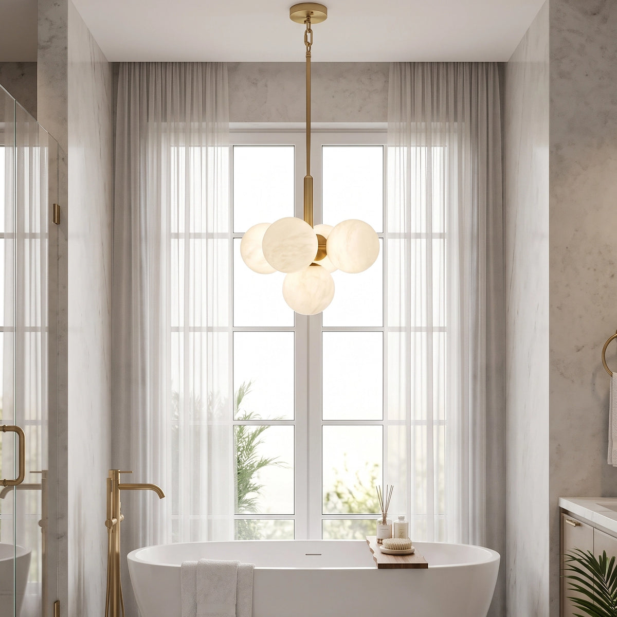 Lune chandelier illuminated above a freestanding bathtub beside a window