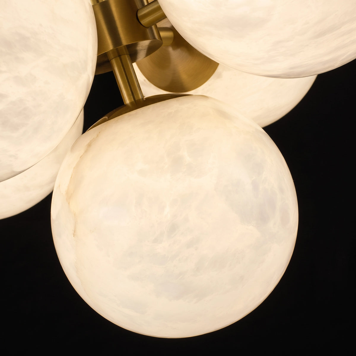 Close-up of illuminated Lune alabaster globes and brass fittings