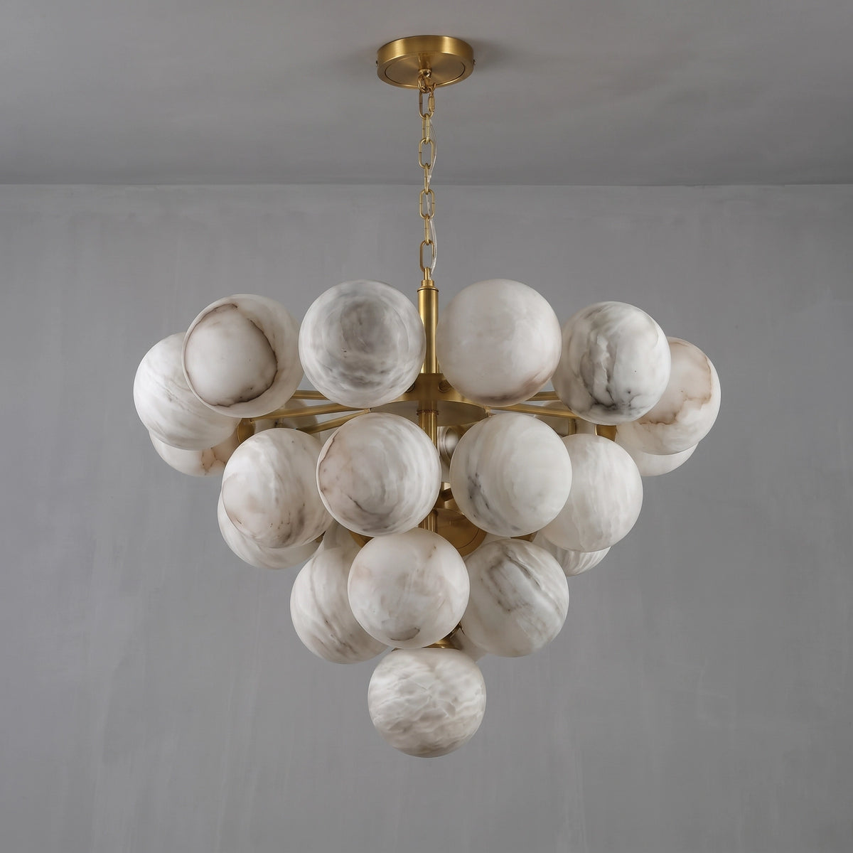 Unlit large Lune chandelier suspended from a brass chain