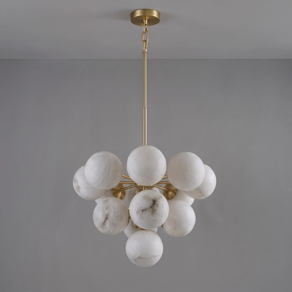 Unlit medium Lune chandelier suspended from a brass rod