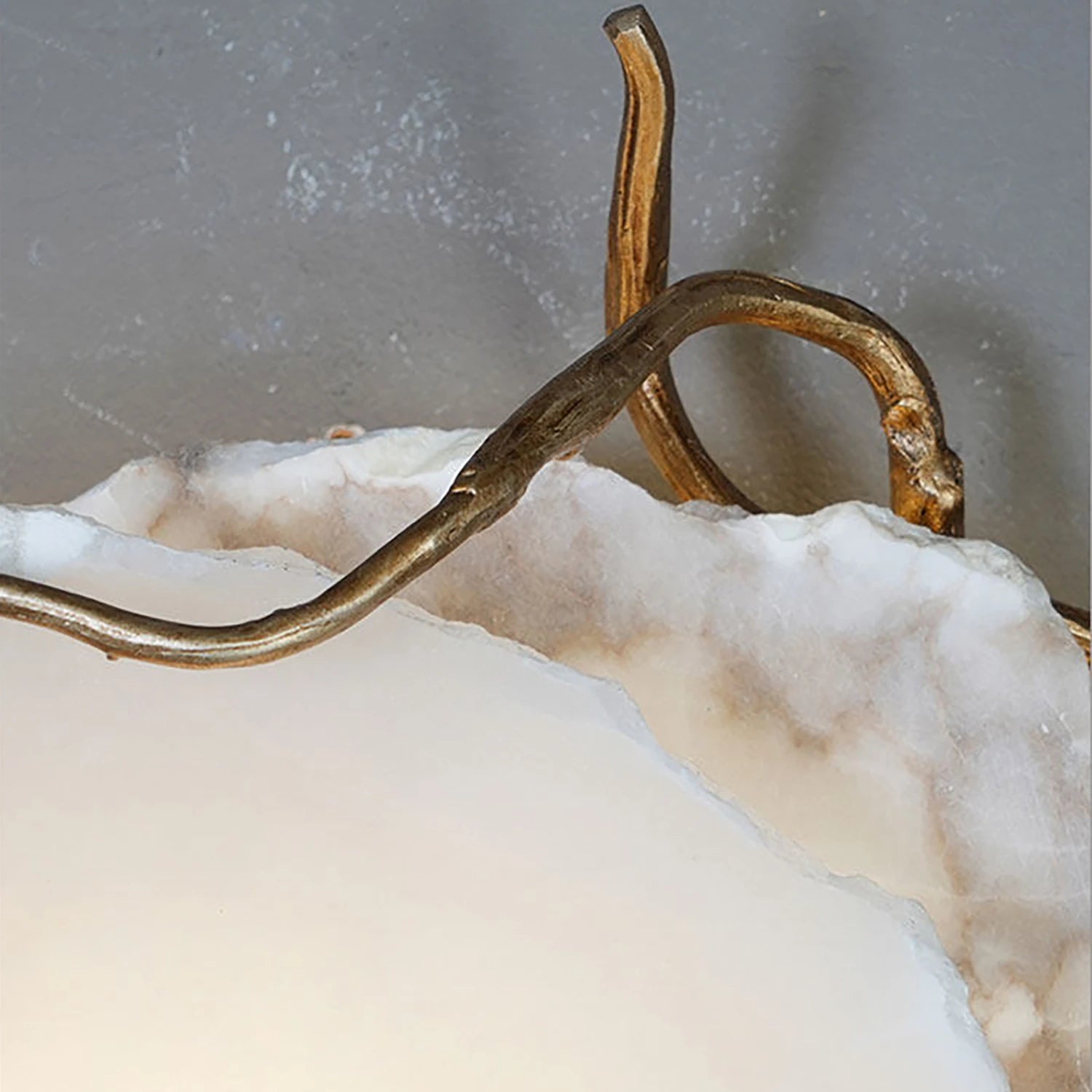 Hand-forged brass branches curling around the edge of a stone slab.