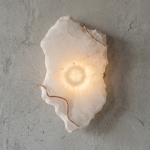 Hand-carved alabaster wall sconce with warm glow and copper accents, modern stone lighting