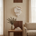 Hand-carved alabaster wall sconce with gold accents, glowing softly in a modern living room.