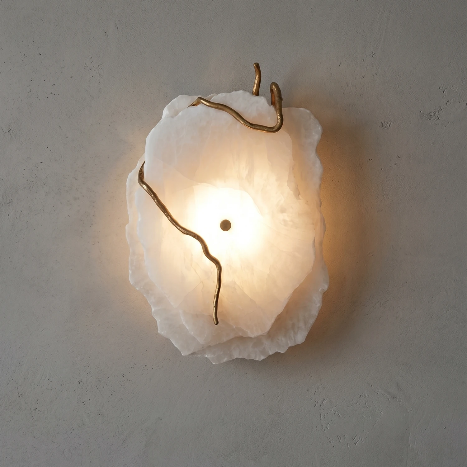Hand-carved alabaster wall sconce with gold accents, emitting warm ambient glow