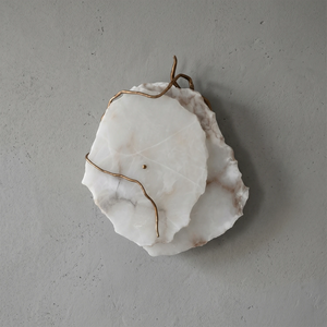 Hand-carved alabaster wall sconce with brass wire accents, modern organic design for ambient lighting