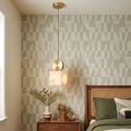 Perrin alabaster mini pendant hanging beside a bedside table against patterned wallpaper