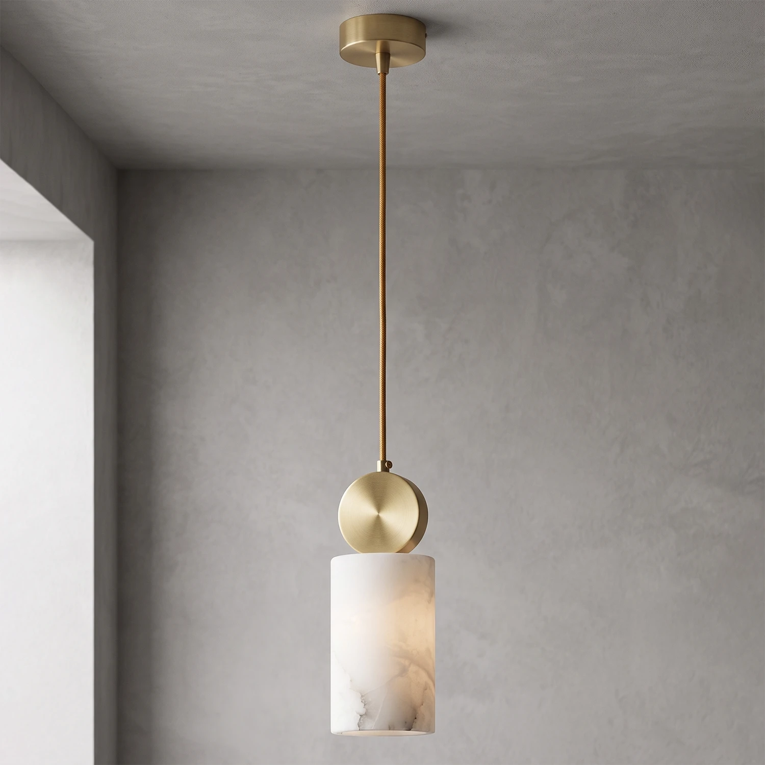 Cylinder alabaster shade glowing warm against a grey wall corner