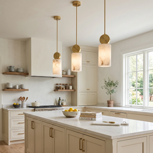 Three cylinder alabaster pendants lighting a bright white kitchen island