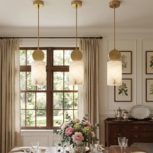 Three cylinder alabaster pendants above a vintage wooden dining table