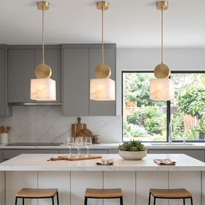 Row of three alabaster pendants over a dark grey kitchen island