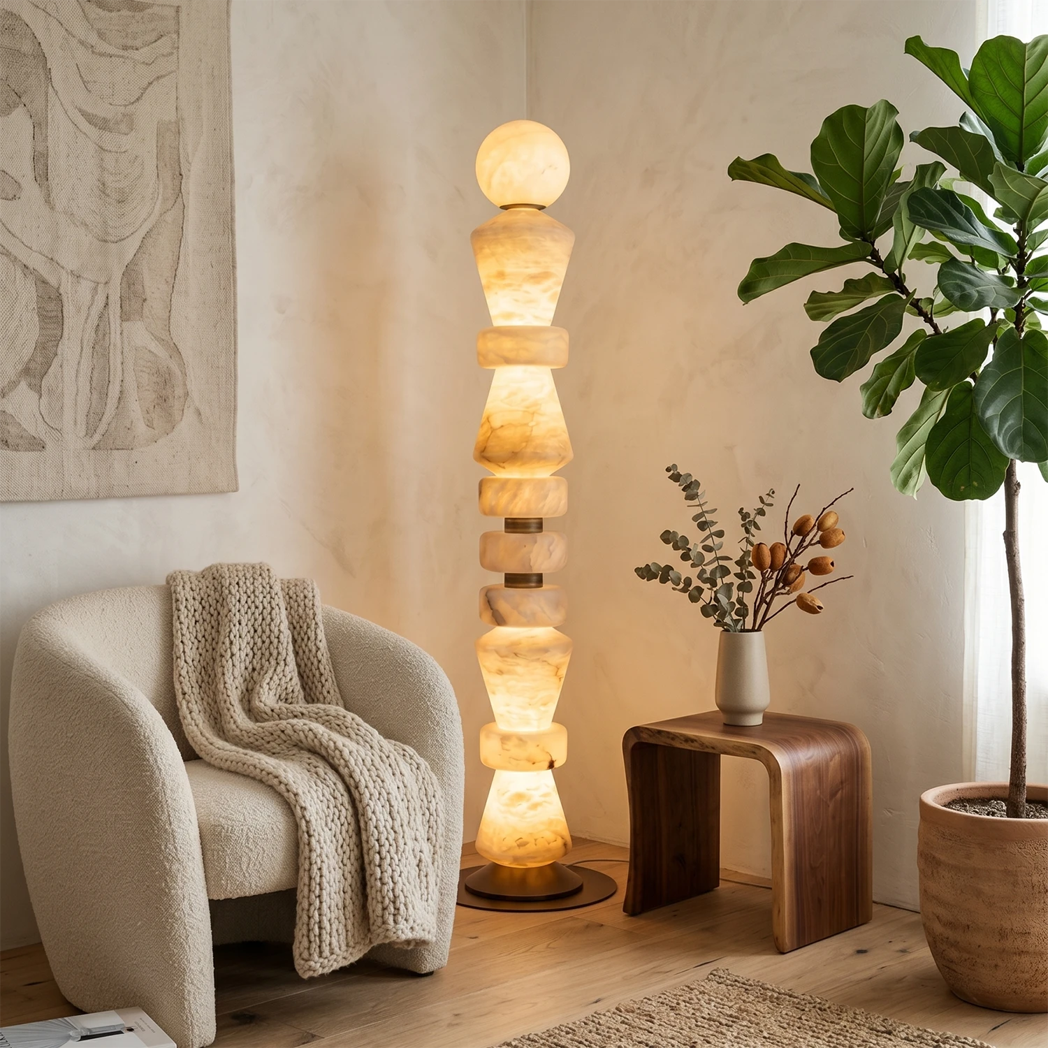 The Totem Stacked Alabaster Floor Lamp beside a boucle armchair in a living room.