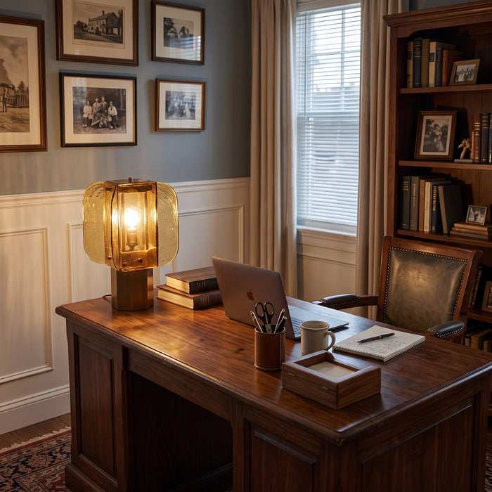 The Tramonto lamp lit on a walnut desk in front of a bookcase.